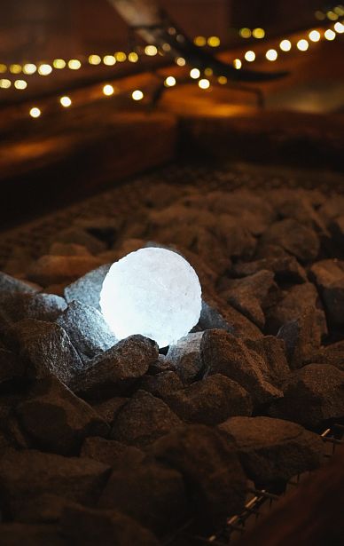 Ein leuchtender, runder Kristallball liegt inmitten dunkler, unregelmäßiger Steine. Die Umgebung wirkt mystisch und stimmungsvoll beleuchtet.