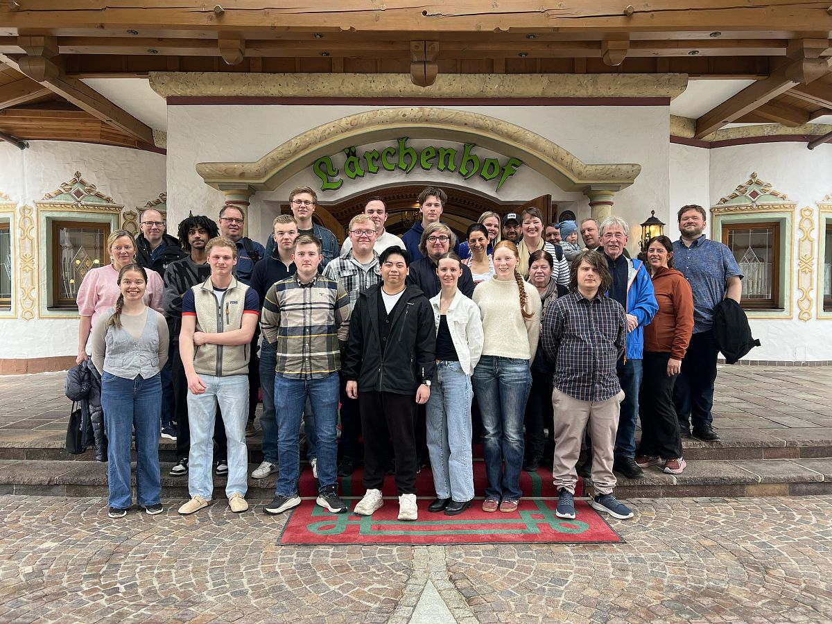 Eine Gruppe von Menschen steht vor einem Gebäude mit dem Schriftzug „Edernhof“. Sie lächeln in die Kamera und sind bei sonnigem Wetter auf Steinfliesen versammelt.